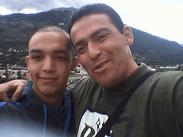 two men posing for a picture with one wearing a shirt that says ' r ' on it
