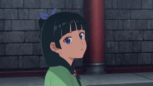 a little girl with a blue bow in her hair is standing in front of a brick wall