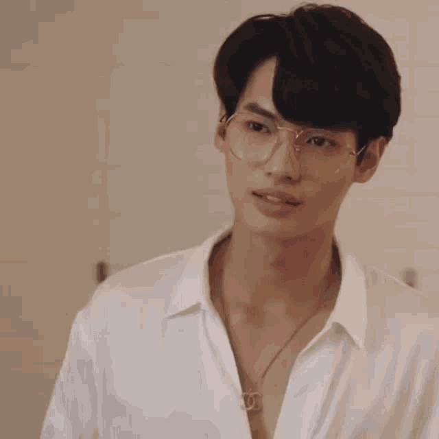 a young man wearing glasses and a white shirt .