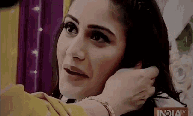 a woman is putting a ring in her ear while looking at the camera .