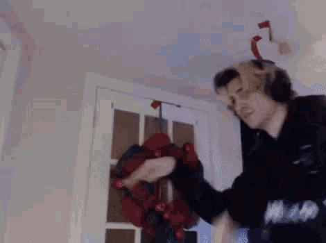 a man wearing headphones is standing in front of a christmas wreath .