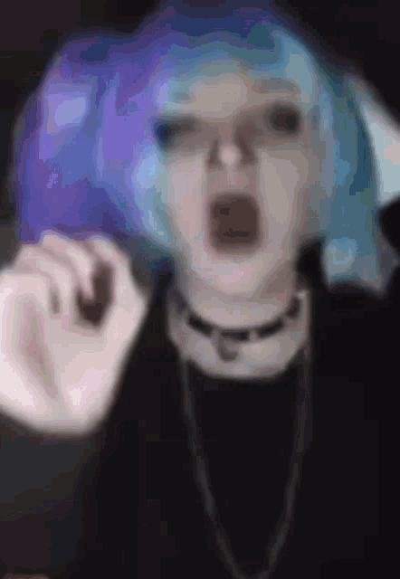 a girl with blue hair and a choker is making a funny face .
