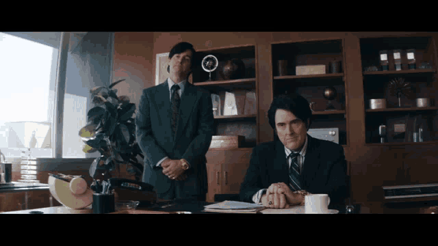 a man sitting at a desk with a cup of coffee