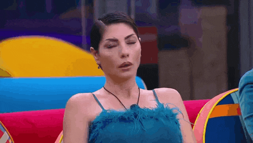 a woman in a blue dress is sitting on a colorful couch .
