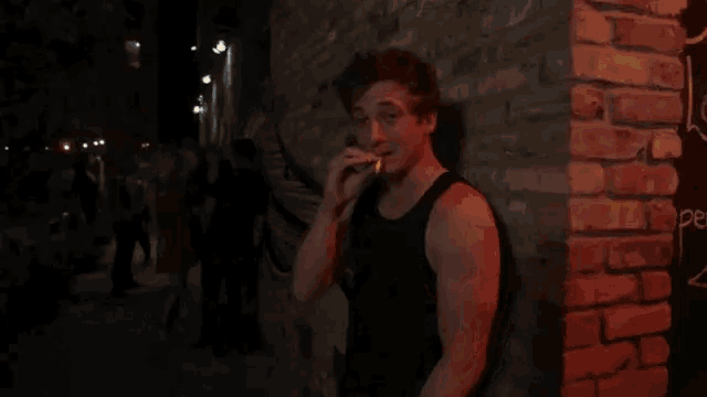 a man is standing in front of a brick wall in a dark room with smoke coming out of it .