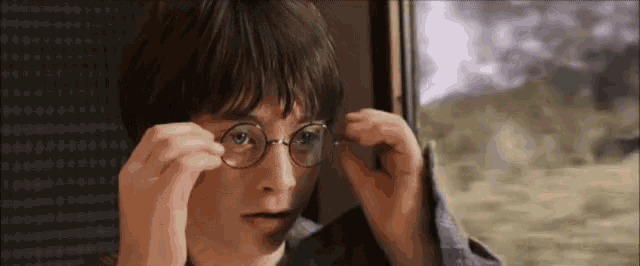a young boy wearing glasses is looking out a window