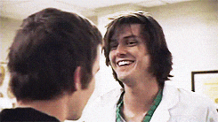 a man in a white lab coat is smiling at another man