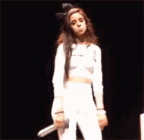 a woman with a bow in her hair is sitting on a stage .