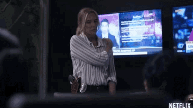 a woman in a striped shirt is standing in front of a screen that says netflix
