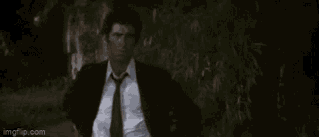 a man in a suit and tie is running through a forest .