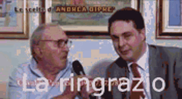 two men are talking into microphones and the words la ringrazo are on the bottom right