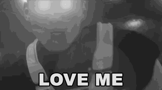 a black and white photo of a man holding a microphone with the words `` love me '' written above him .