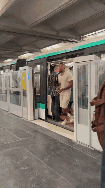 a man in a white shirt is standing in front of a train with the doors open