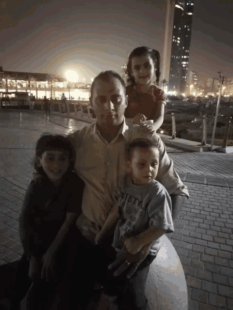 a man holds three children including a boy wearing a shirt that says vista