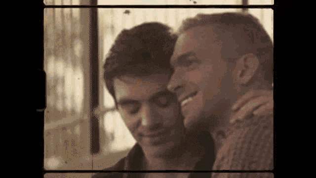 a couple of men are standing next to each other and hugging each other .
