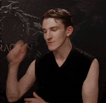 a young man in a black tank top is standing in front of a dragon poster