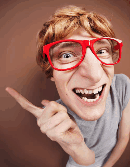 a young man wearing red glasses is pointing up