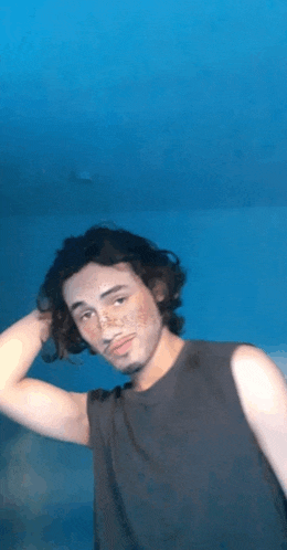 a young man with freckles on his face is standing in front of a blue wall