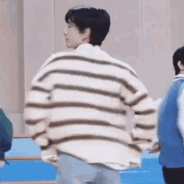 a man wearing a striped sweater is standing in a room .