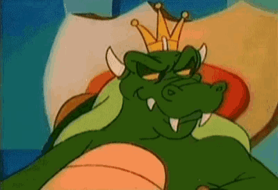 a cartoon crocodile with a crown on his head is laying on a bed .