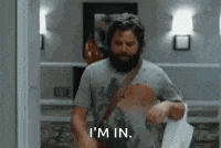 a man with a beard is standing in a room holding a towel and saying `` i 'm in . ''