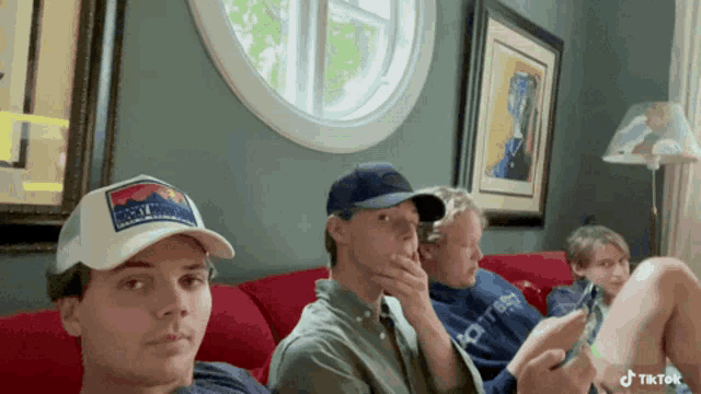 a group of young men are sitting on a couch and one of them has a hat that says rocky mountain