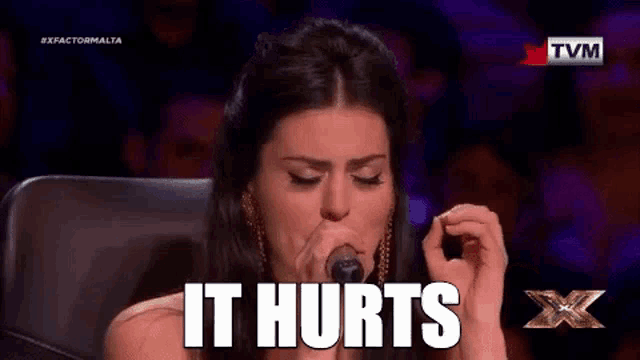 a woman singing into a microphone with the words `` it hurts '' written on the screen .