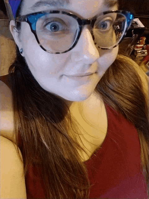 a woman wearing glasses and a red shirt looks at the camera