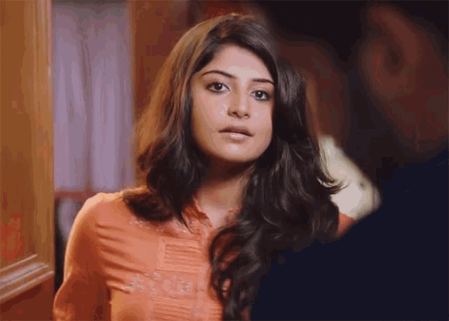 a woman in an orange shirt looks at a man in a blue shirt