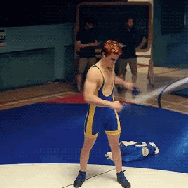 a wrestler in a blue and yellow singlet is standing on a mat