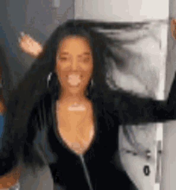 a woman with long black hair is standing in front of a door with her arms outstretched .