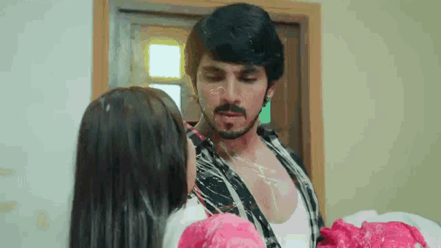 a man and a woman are standing next to each other in a room and the man is covered in milk .