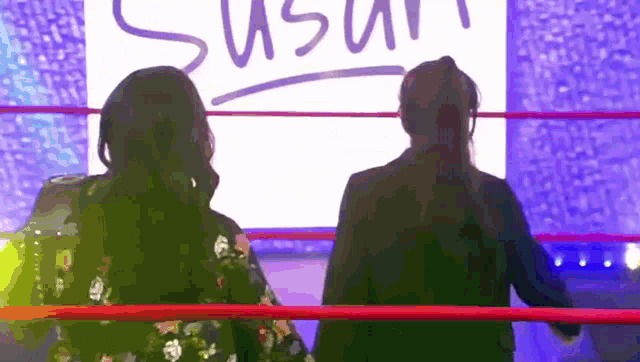 two women in a wrestling ring with a sign that says susan in the background