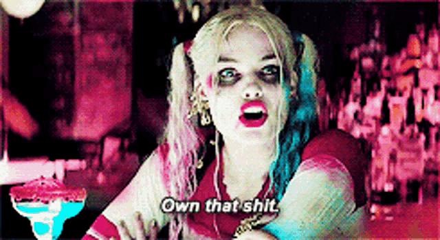 a woman in a harley quinn costume says " own that shit " in a bar