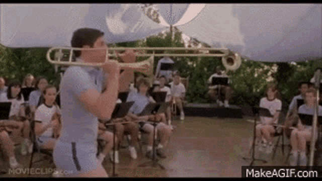 a man is playing a trombone in front of a band in a movie .