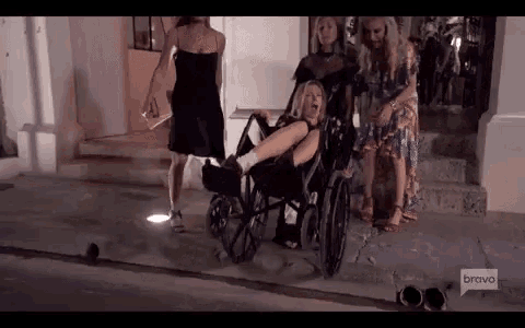 a woman in a wheelchair with a bandaged leg is being pushed by two other women .