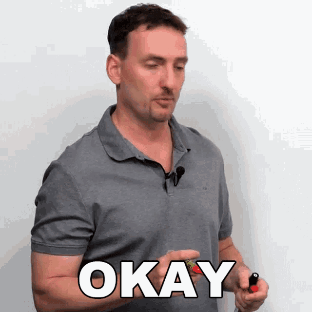 a man in a grey shirt is holding a red lighter and says okay