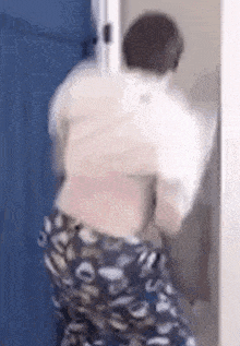 a man in a white shirt and blue pants is standing in front of a door .
