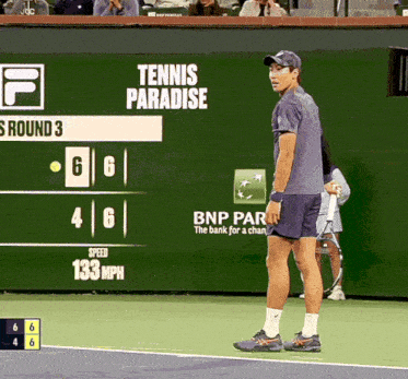 a tennis player stands in front of a tennis paradise sign