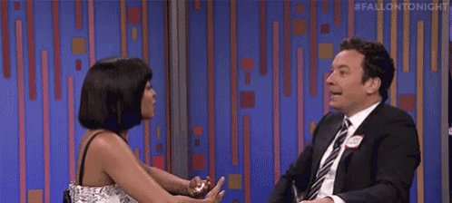 a man in a suit and tie is laughing while talking to a woman in a dress .