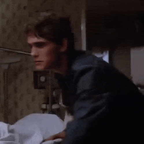 a young man is laying in a hospital bed next to a sick person .