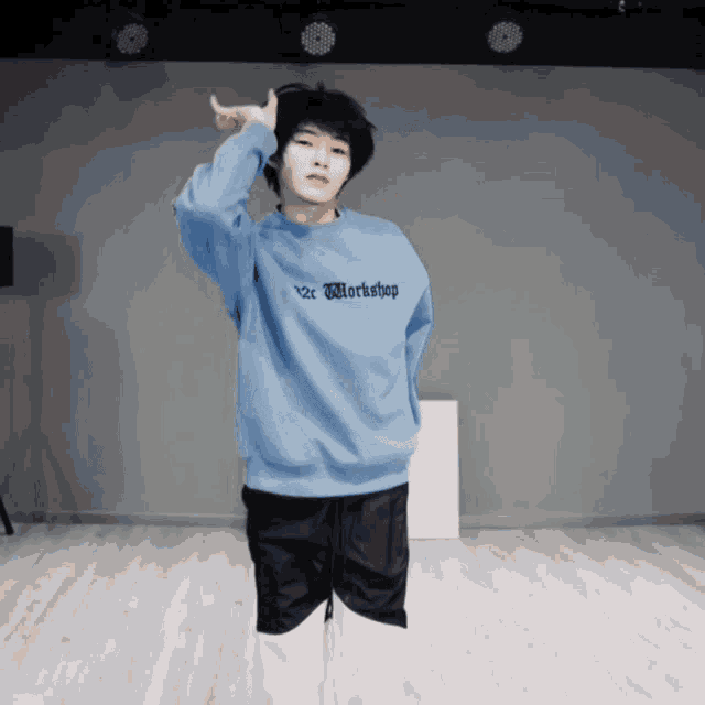 a young man wearing a blue sweater that says workshop on it