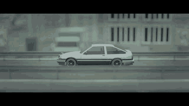 a white toy car is driving down a highway in front of a building