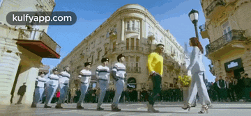 a group of people are marching down a street in front of a building with the words kulfyapp.com on the bottom right