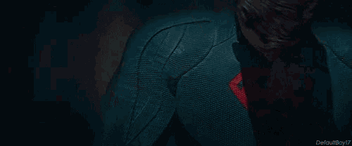 a man in a red and black superhero costume is standing in the dark .