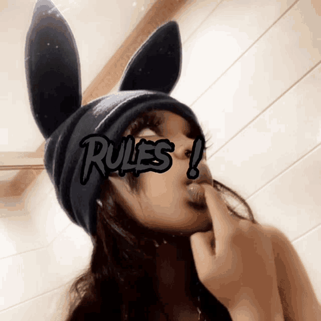 a woman wearing bunny ears and a hat with the word rules on her face