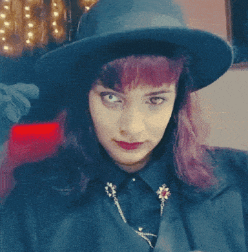 a woman with purple hair wearing a hat