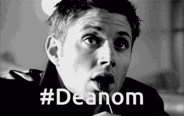 a black and white photo of a man eating a lollipop with the hashtag #deanom above him .