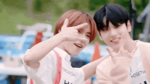 two young men are posing for a picture and making a peace sign with their hands .