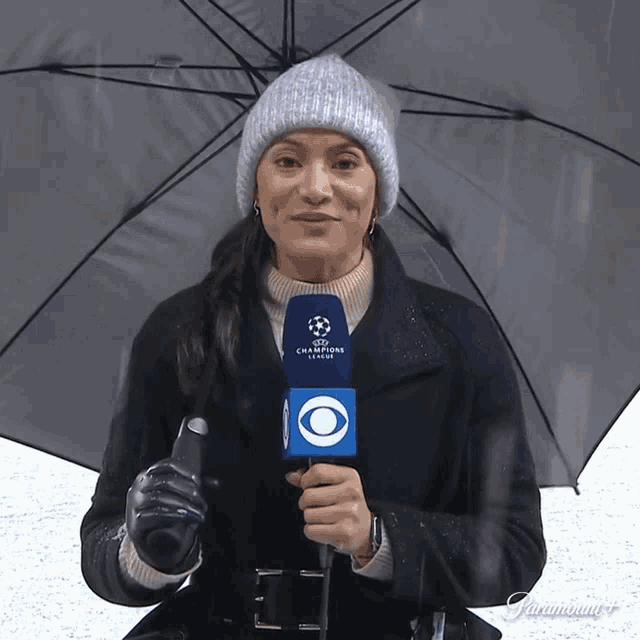 a woman is holding an umbrella and a microphone that says champions league